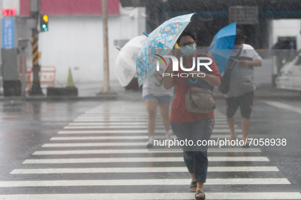 People with umbrellas walk in strong rains and winds in Keelung, as Typhoon Chanthu bringing torrential rains and damaging winds makes landf...