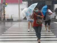 People with umbrellas walk in strong rains and winds in Keelung, as Typhoon Chanthu bringing torrential rains and damaging winds makes landf...