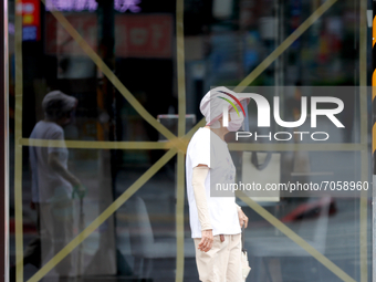 People walk past a window taped with an X sign outside a store in strong rains and winds in Taipei, as Typhoon Chanthu bringing torrential r...