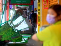 People with umbrellas walk past collapsed barricades in strong rains and winds in Keelung, as Typhoon Chanthu bringing torrential rains and...