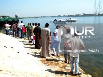 Egyptians watch rescue workers look for victims of a passenger boat after it sunk in the river Nile in Giza, south of Cairo, Egypt, Thursday...