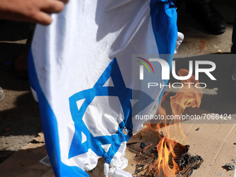 Palestinians burn an Israeli flag during a rally next the Red Cross building in Gaza City in support of more than a thousand prisoners who a...