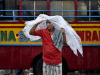 A migrant labour carries plastic as his shelter during heavy rainfall in Kolkata, India, 14 September, 2021.  (