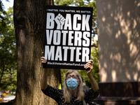 A woman holds a sign as members of Congress speak at the “Finish the Job: For the People” voting rights rally At the Robert A. Taft Memorial...