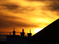 The sun is seen setting behind a row of chimneys in Warsaw, Poland on September 16, 2021. (