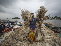 Workers load jute on a boat in the bank of Padma River at a rural market in Munshigonj on September 17, 2021.  (