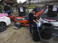 Staff members of the Ratchaphruek Taxi Cooperative prepare sprinkle water to plant vegetables on unused abandoned taxi cars parked at Ratcha...