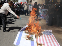 A Palestinian protester burns American and Israeli flags during a rally next the Red Cross building in Gaza City, on September 19, 2021. whe...