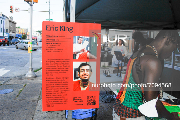 A Germantown resident looks through tabled information on political prisoners. A placard providing information on Anarchist Eric King, arres...