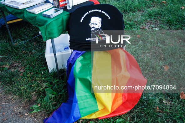 An LGBTQA flag rests on a chair near an information table in Tubman Park held in place by a T-Shirt advocating for political prisoner Russel...