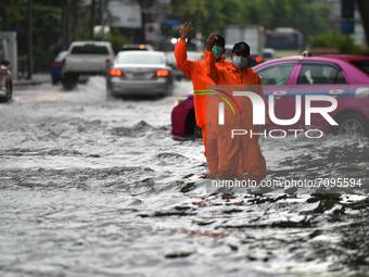 Municipal officials wearing a rain coat regulate the traffic on a water-logged road during a heavy rain in Bangkok on September 19, 2021 in...