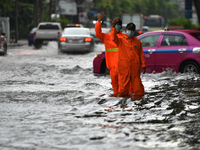 Municipal officials wearing a rain coat regulate the traffic on a water-logged road during a heavy rain in Bangkok on September 19, 2021 in...