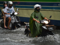 People wearing a rain coat ride their motorcycle through a water-logged road during a heavy rain in Bangkok on September 19, 2021 in Bangkok...