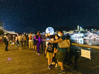 Hong Kong, China, 21 Sep 2021,  A family takes  a selfie in front of the 15-m inflatable moon in Kwun Tong Promenade. (