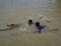 Indian boys crosses the flooded River Ganges with help of bundle of bamboo sticks,in Allahabad on July 29,2015.The water level of River Gang...