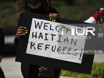 A demonstrator stands in front of the Leland Federal Building in Houston, Texas, holding a sign that reads, 