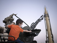 An Iranian young boy plays with an anti-aircraft gun while visiting a war exhibition which is held and organized by the Islamic Revolutionar...