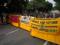 Security personnel stand guard behind barricades as protesters installed banners on them during a global climate strike as part of the 'Frid...
