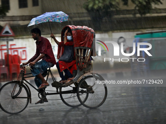 A passenger holds an umbrella as a rickshaw puller rides through light rain in Dhaka, Bangladesh on September 25, 2021.  (