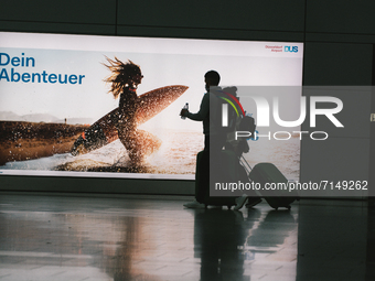 two travellers walk pass a big duesseldorf airport advertising sign at Duesseldorf airport on September 29, 2021 (