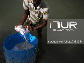 A Worker washes medical staff in the river Buriganga in Dhaka, Bangladesh on September 29, 2021.  Buriganga River, which flows by Dhaka city...
