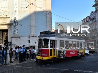 A tram runs near a group of people walking in the streets of the Chiado district, Lisbon, 29 September 2021. Portugal is gradually returning...