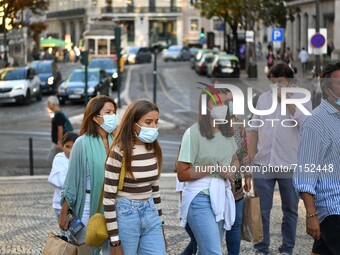 People wearing protective masks walk through the Chiado district of Lisbon, Portugal on September 29, 2021. Portugal is gradually returning...