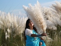 A girl holds catkins at a field in Sarighat on the outskirts of Dhaka, Bangladesh on September 30, 2021. (
