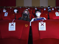 Shopping mall staff sit inside a cinema theater to demonstrate restricted sitting arrangements at a cinema inside a major shopping mall in B...