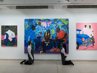 LONDON, UNITED KINGDOM - OCTOBER 08, 2021: Staff members pose with (L-R) 'Greatness is Within', 2021, by Anjel, 'Blue night romance', 2019,...