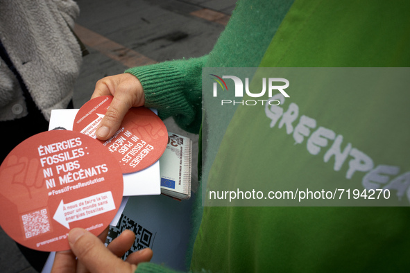 A Greenpeace member holds stickers reading 'Fossil fuels: no advertising, no sponsorship'. Greenpeace Toulouse organized a play in the cente...