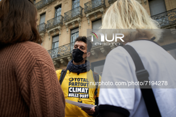 A Greenpeace member explains to two women why the play. He wears a shirt reading 'Total everywhere, climate nowhere'. Greenpeace Toulouse or...