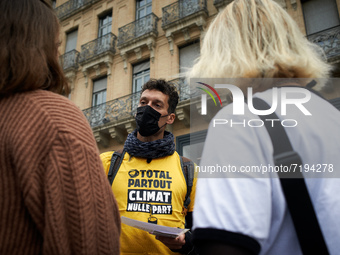 A Greenpeace member explains to two women why the play. He wears a shirt reading 'Total everywhere, climate nowhere'. Greenpeace Toulouse or...