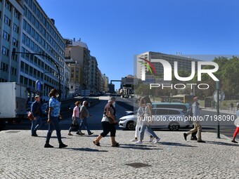 People wearing a protective mask walk near the Marques de Pombal monument, Lisbon. 07 October 2021. Portugal has about nine million people v...