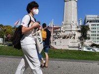 People wearing a protective mask walk near the Marques de Pombal monument, Lisbon. 07 October 2021. Portugal has about nine million people v...