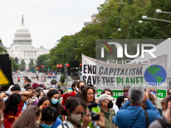 Protesters carry a sign linking capitalism to the climate crisis as Native American activists lead a march from Freedom Plaza to the White H...