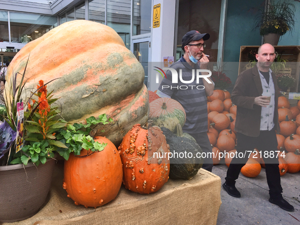 Men walk past a giant pumpkin displayed outside a supermarket during the Autumn season in Markham, Ontario, Canada, on October 15, 2021. 