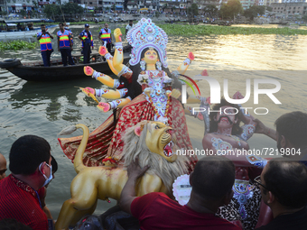 Hindu devotees immerse a clay idol of the Hindu Goddess Durga in the Buriganga River on the final day of the Durga Puja festival in Dhaka, B...