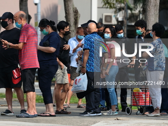 People wearing protective mask wait in queue to take their COVID-19 antigen rapid test outside a quick test centre on October 16, 2021 in Si...