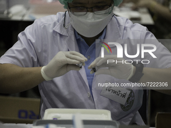 Medical personnel shaking the Pfizer vaccine before it is inserted into syringes in Nonthaburi province at Hall 5, Impact Arena, Muang Thong...