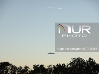 A plane flyes above the trees during the evening hours in Stuttgart, Germany on October 9, 2021 (
