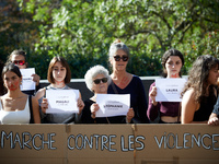 Women show papers with the name of women killed behind a cardboard reading 'March against violences'. Women from the collective NousToutes o...