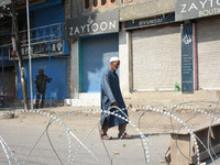 A Kashmiri man walks past the concertina wire during a gun battle between Indian Forces and militants in Pampore area of Pulwama district s...