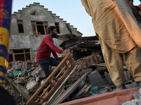 Kashmiri people assess the damaged residential houses  near the gun battle site in Pampore area of Pulwama district south of Srinagar, India...