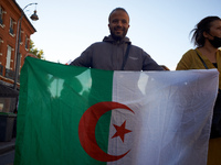 A protester holds an algerian flag. Dozens of protesters walk to commerorate the 60th anniversary of the slaughter of algerian protesters by...