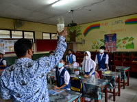 Students attend a lesson in a classroom at a primary school during its reopening as a small number of Bogor's students head back to their sc...