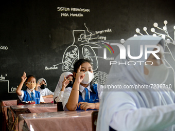 A student wear protective face masks in a classroom at a primary school during its reopening as a small number of Bogor's students head back...