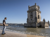 A person wearing a protective mask stands near the Torre de Belem tourist area in Lisbon. 20 October 2021.  Most regions in mainland Portuga...