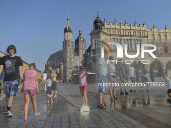 People having fun running and walking through a water sprinkler in the main square in Krakow's Old Town as temperatures reach 35 degrees. Th...