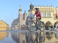 A cyclist goes through a water sprinkler in the main square in Krakow's Old Town as temperatures reach 35 degrees. The hit wave that was alr...